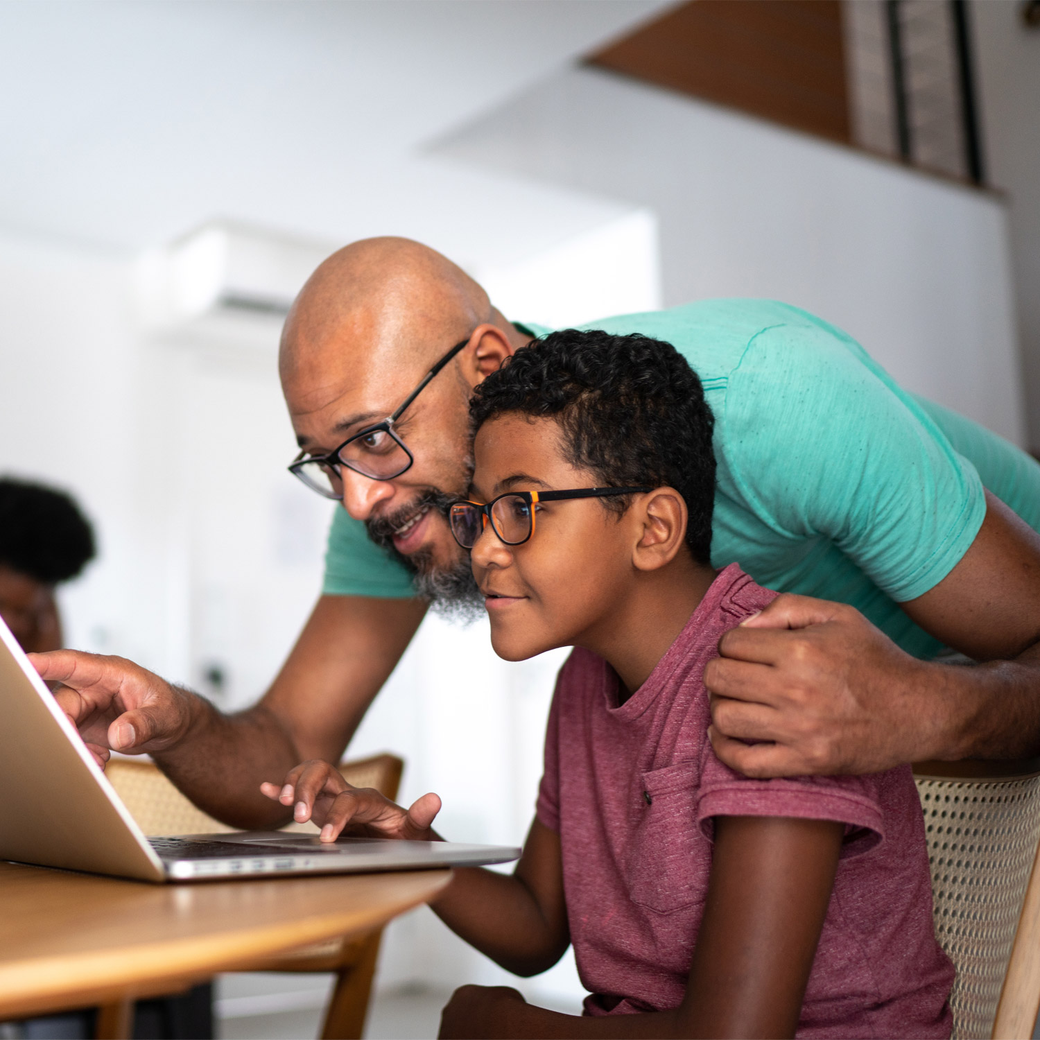 A male teacher helps a student with a computer program.