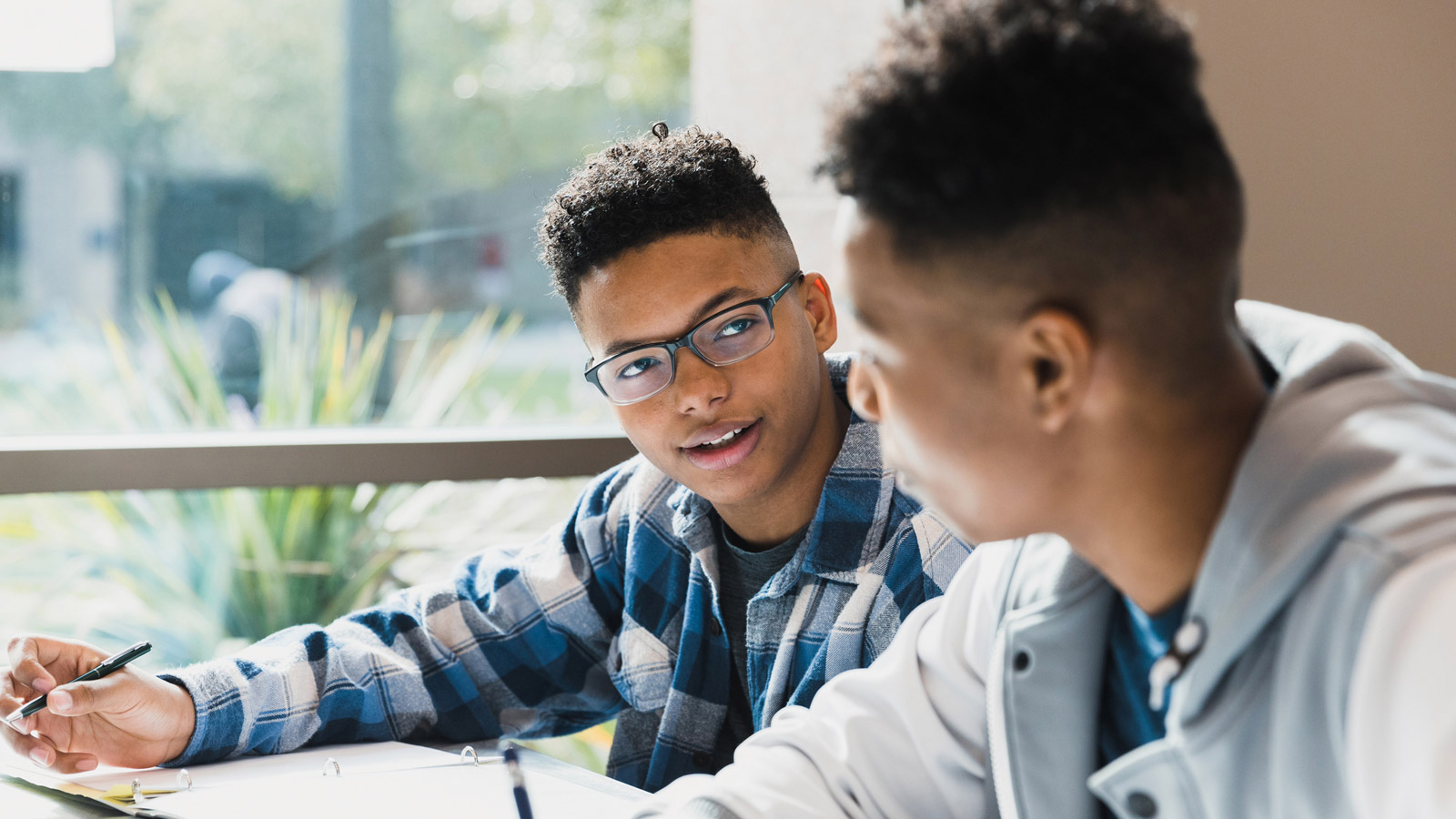 Two high school teenagers work on their homework together.