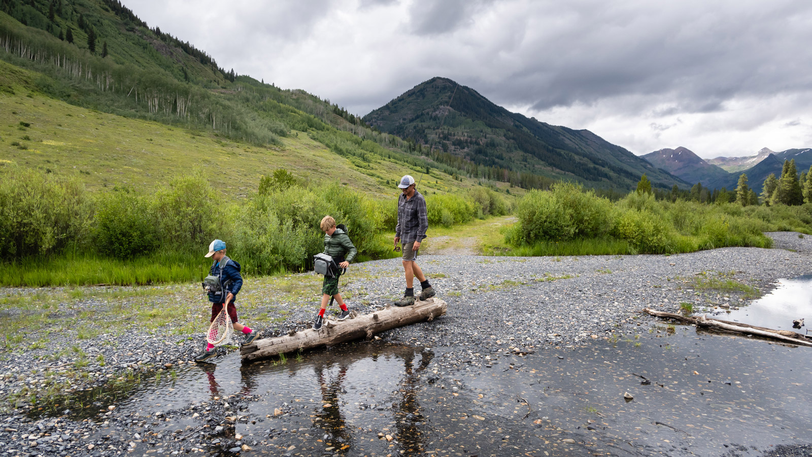 Father and sons hiking with fishing gear in the wilderness.