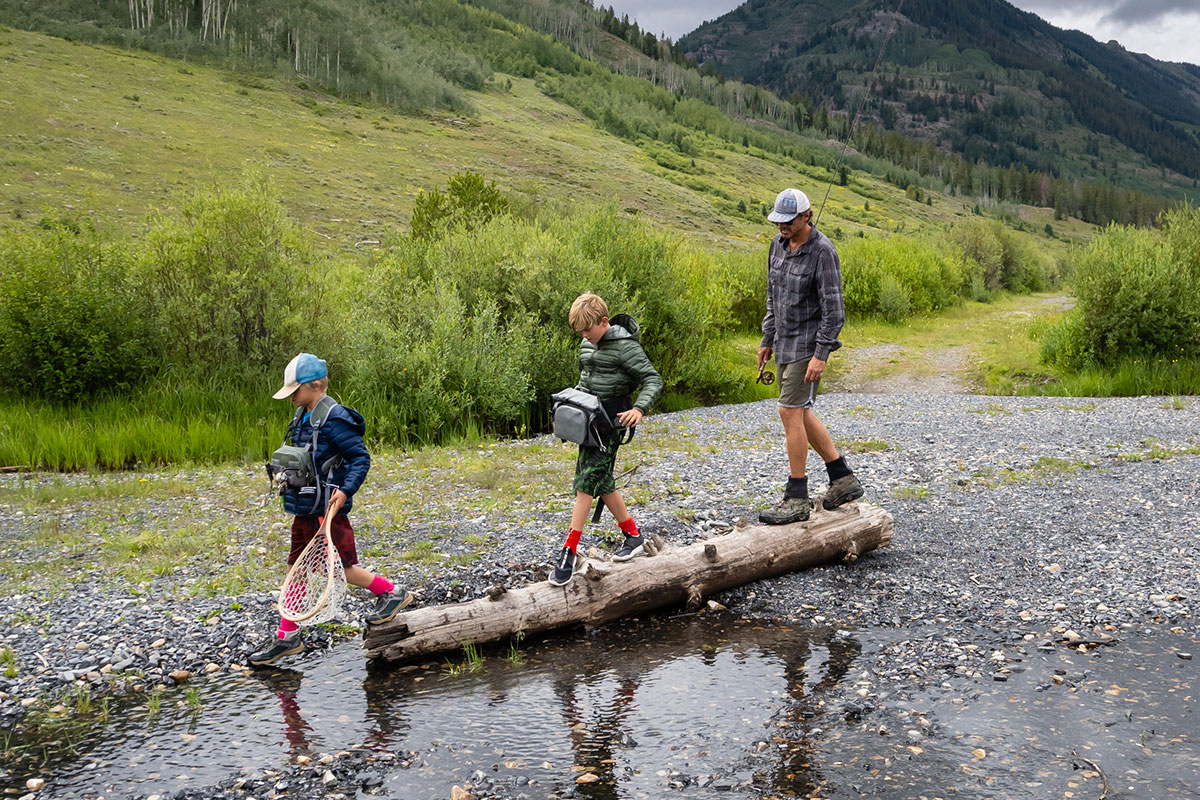 Father and sons hiking with fishing gear in the wilderness