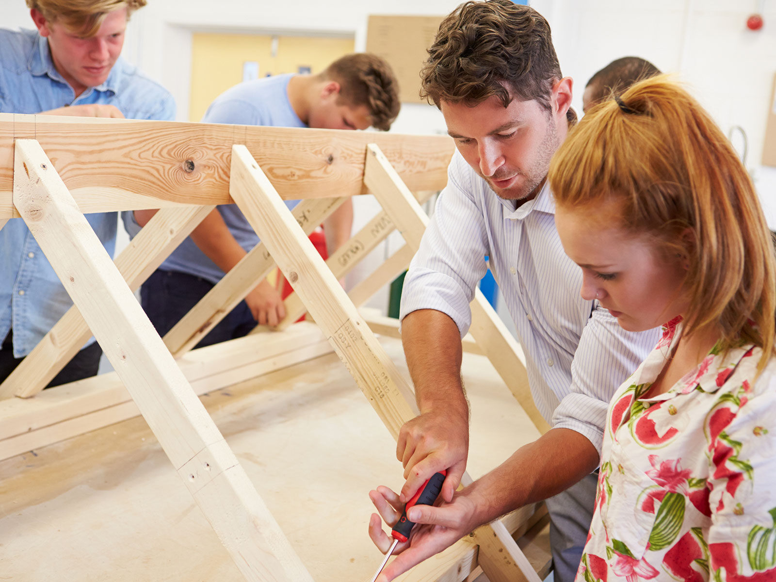 Woodworking teacher demonstrating craft to high school students.